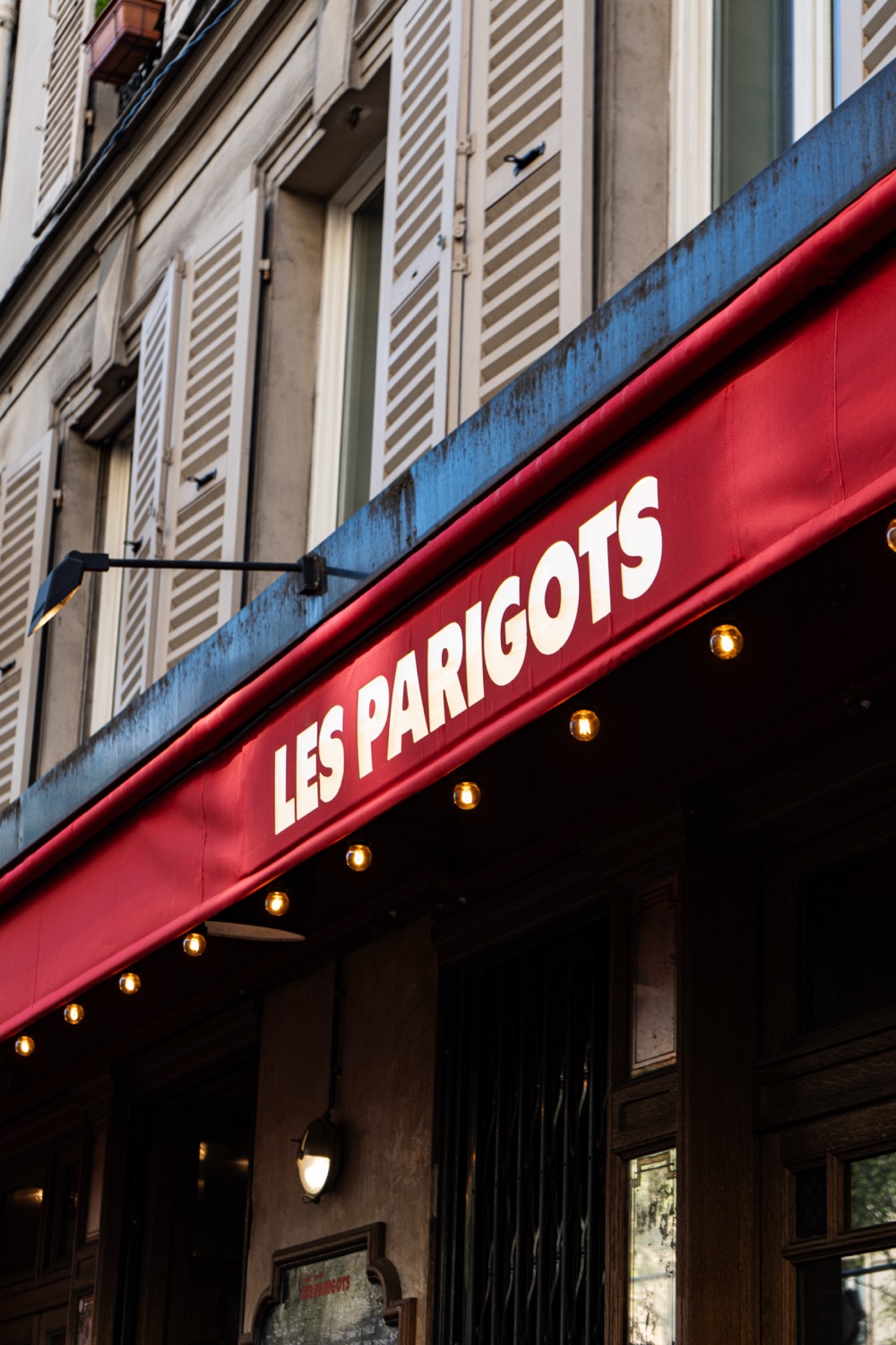 L'enseigne rouge Les Parigots sur la façade du bistrot