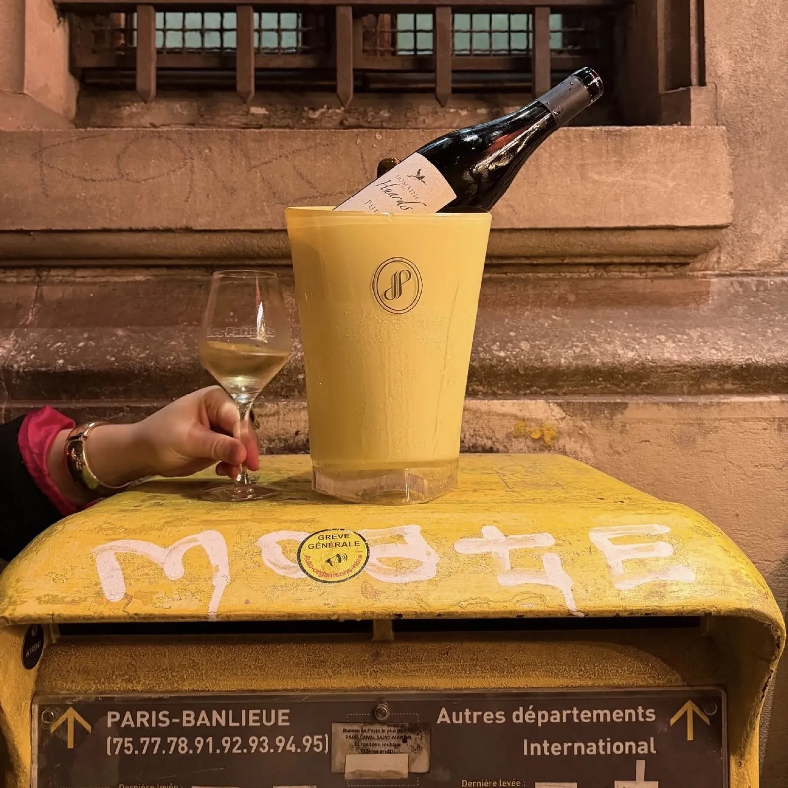 Bouteille de vin blanc au frais dans un seau, verre à la main