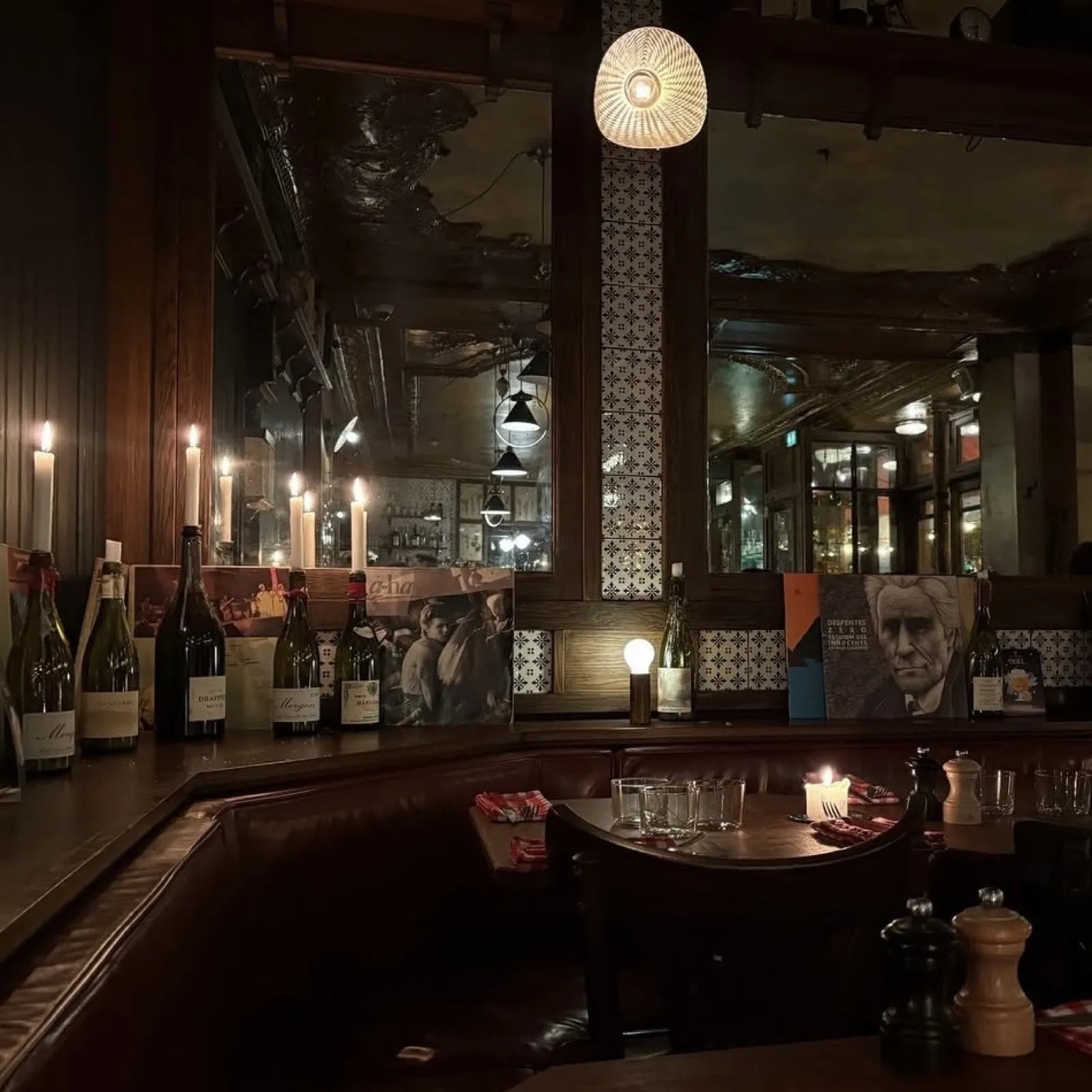 Banquettes en cuir, bougies et miroirs dans la salle des Parigots le soir