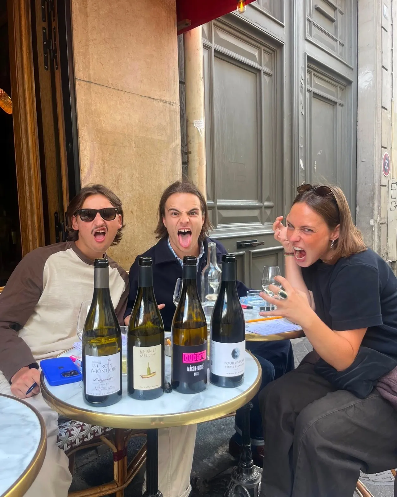 Amis attablés en terrasse avec des bouteilles de vin