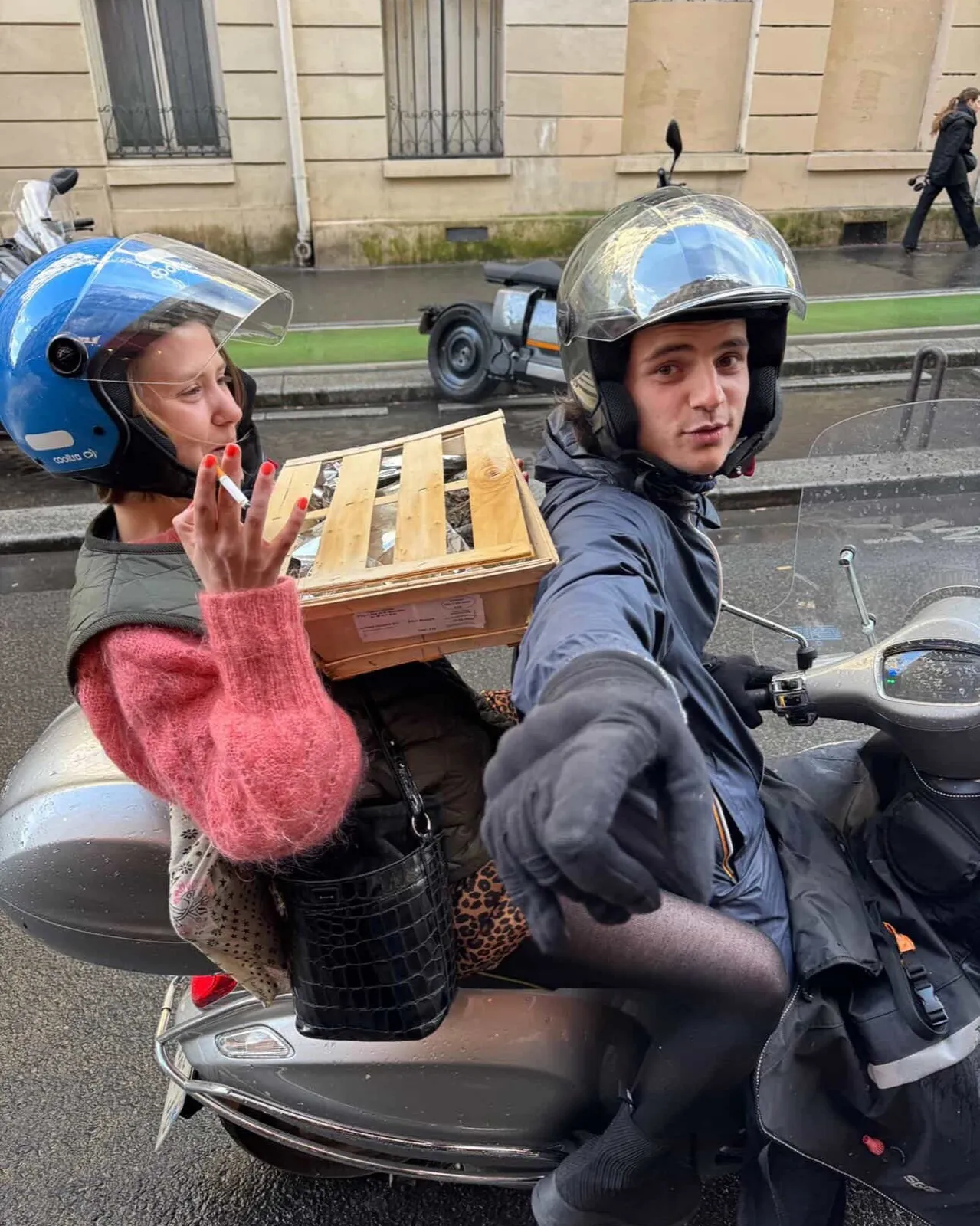 Deux membres de l'équipe en scooter avec une cagette, dans la rue