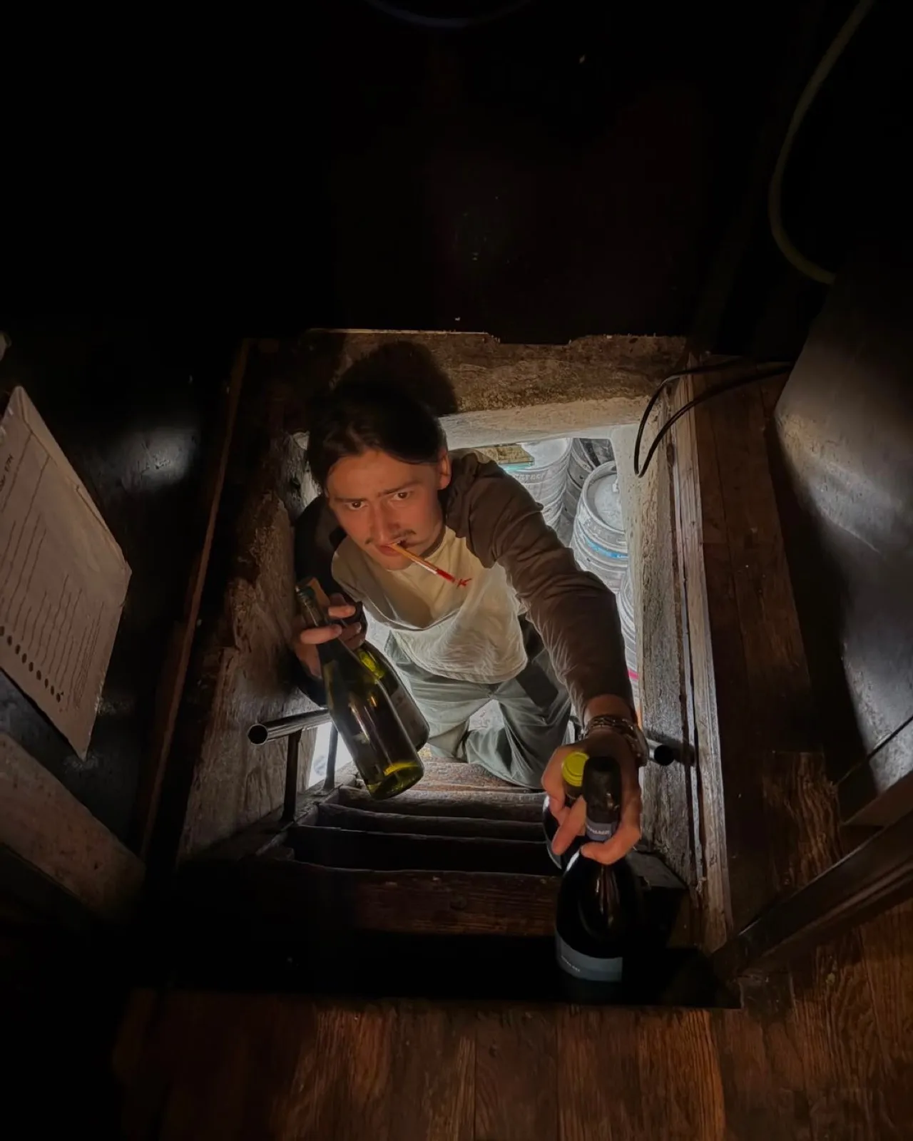Un membre de l'équipe remonte des bouteilles par la trappe de la cave